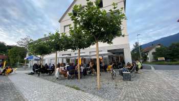 Terrasse animée du St. Martins Pub am Platz avec des arbres ombragés et des clients attablés