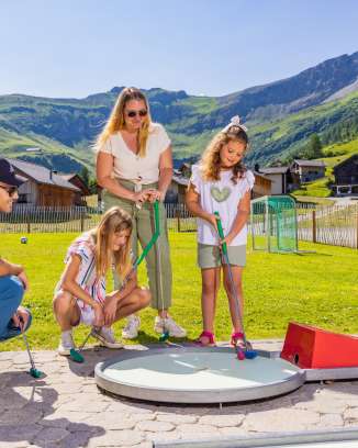 Une famille joue au minigolf dans le village de montagne ensoleillé de Malbun, au Liechtenstein