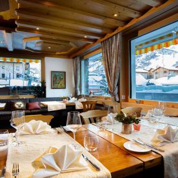 Salle de restaurant lumineuse et accueillante avec une grande baie vitrée et une vue sur les montagnes enneigées.