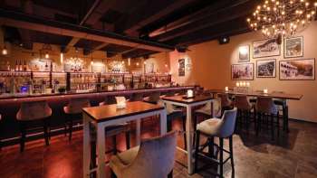 Intérieur élégant du restaurant avec des éléments en bois foncé, un espace bar et des chaises confortables dans une ambiance chaleureuse.
