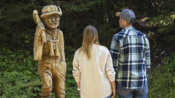 Les promeneurs observent les figures en bois sculptées le long du « sentier des légendes walsers ».
