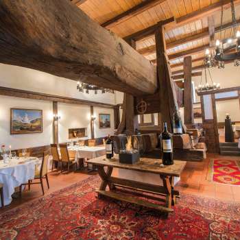 Salle à manger rustique avec poutres en bois d'époque, cheminée et tables dressées au restaurant Torkel.