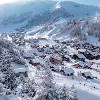 Maisons enneigées et pistes de ski dans le village alpin hivernal de Malbun, niché dans un paysage montagneux de rêve.