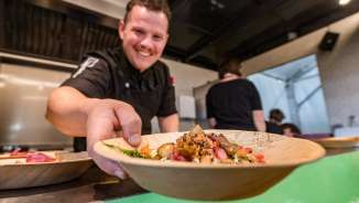 Un cuisinier sert une assiette avec un plat régional au festival du goût de Vaduz, Liechtenstein - un événement culinaire axé sur le goût