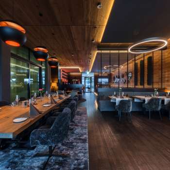 Salle de restaurant élégante avec des éléments d'éclairage modernes et des revêtements en bois sur les murs.