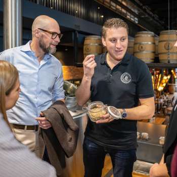 Un employé explique les ingrédients de la bière à un groupe de clients intéressés lors d'une visite guidée de la brasserie.