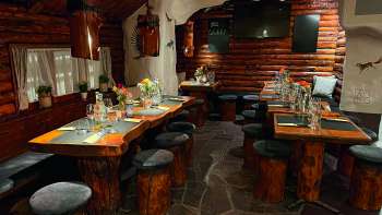 Vue sur un restaurant à l'aménagement rustique avec des meubles en bois, des tables décorées en vert et des bougies.