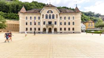 Bâtiment du gouvernement de Vaduz avec une façade claire et une place devant.