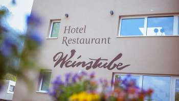 Vue de la plaine alluviale du restaurant Weinstube avec des fleurs au premier plan 
