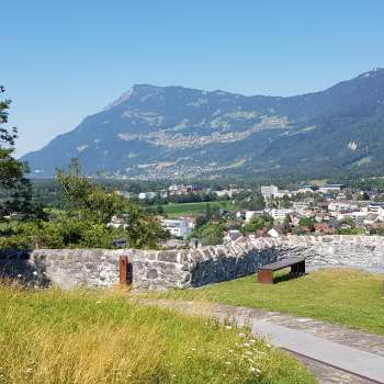 Promenade à travers une allée d'arbres avec vue sur le château de Gutenberg et le décor alpin en arrière-plan