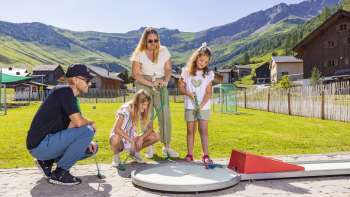Une famille joue au minigolf sur le minigolf des Alpes à Malbun Une famille joue au minigolf sur le minigolf des Alpes à Malbun