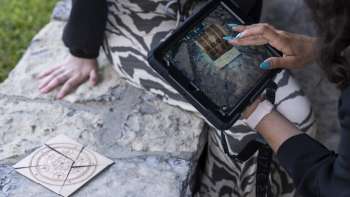 Une joueuse utilise son iPad pour résoudre une énigme dans une salle d'aventure en plein air