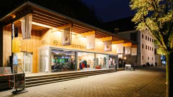 Centre d'accueil moderne avec façade en verre à Vaduz la nuit, éclairé de manière accueillante.