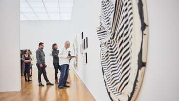 Groupe de visiteurs dans la salle d'exposition du Musée des Beaux-Arts, au premier plan une grande œuvre d'art ronde