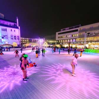 Personnes patinant sur la patinoire éclairée de Vaduz on Ice dans le centre-ville de Vaduz le soir