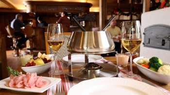 Gros plan sur un service à fondue au fromage avec du pain frais, des légumes et du vin dans une ambiance élégante