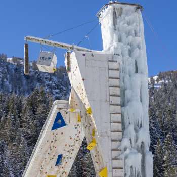 Tour de glace gelée à Malbun avec des voies d'escalade et des points d'ancrage visibles, contre un ciel bleu