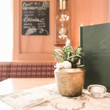Détail d'une table dressée avec des cartes de menu, des fleurs et une décoration rustique