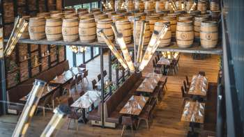 Salle de brasserie accueillante avec de longues tables en bois, des décorations de tonneaux et un éclairage stylé