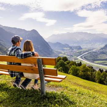Couple sur un banc en bois avec vue sur la vallée du Rhin et les montagnes.