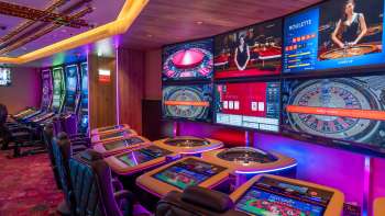 Tables de jeu modernes avec écrans numériques et plusieurs options de roulette et de jeux de cartes dans le casino de Schaanwald à l'éclairage d'ambiance.