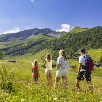 Une famille se promène dans une prairie d'été fleurie à Malbun, au Liechtenstein, en admirant la vue sur les Alpes environnantes.