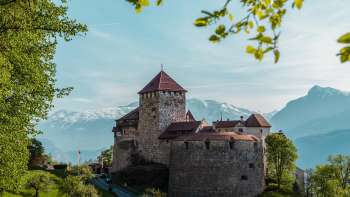 Vue pittoresque sur le château de Vaduz, niché dans des collines et des forêts verdoyantes.