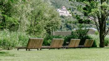 Pelouse avec chaises longues en bois avec vue sur le château de Vaduz