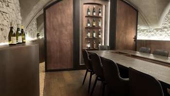 Elégante salle de dégustation du WY Weinbar avec plafond voûté et table en bois noble pour des dégustations de vin exclusives.