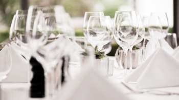 Gros plan sur plusieurs verres à vin empilés sur une table blanche avec des reflets lumineux.