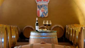 Vue de la cave à vin avec des tonneaux en bois et une table couverte de vins et de fromages dans la cave du Prince du Liechtenstein