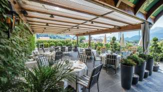 Terrasse couverte du restaurant Torkel à Vaduz, entourée de plantes et avec vue sur les Alpes