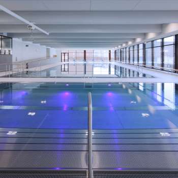 Piscine intérieure moderne à Triesen avec bassin éclairé et grande façade vitrée.