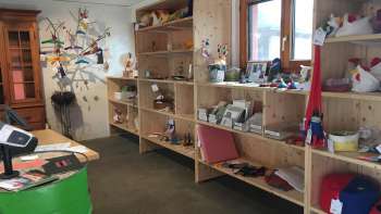 Intérieur du magasin Birkahoflädile avec des étagères en bois remplies de produits régionaux, décorées avec des éléments colorés - magasin à la ferme au Liechtenstein.