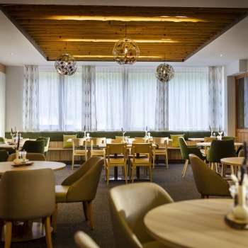 Un autre coin de la salle à manger, avec les mêmes tables rondes, une ambiance chaleureuse et des installations lumineuses modernes.