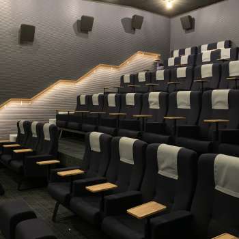 Salle de cinéma moderne au Skino de Schaan avec des sièges confortables, des petites tables et un éclairage tamisé.