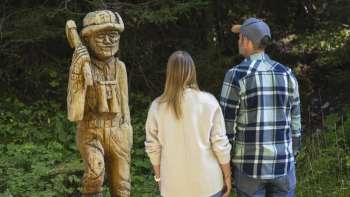 Les promeneurs observent les figures en bois sculptées le long du « sentier des légendes walsers ».