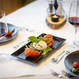 Salade fraîche de tomates et mozzarella avec vin rouge sur une table dressée au JUFA Hotel Malbun