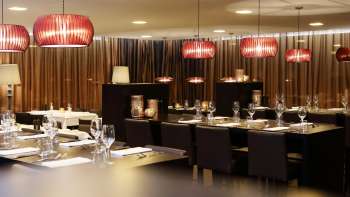 Salle de restaurant élégante avec des meubles sombres, des lampes design rouges et une ambiance raffinée