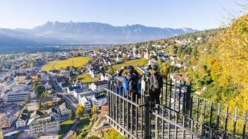 Randonneurs à la balustrade du point de vue de Känzile avec vue panoramique sur Vaduz et les montagnes environnantes.