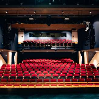 Vue depuis la scène sur les rangées de sièges rouges et la technique d'éclairage dans la salle de spectacle moderne du TAK Theater Liechtenstein