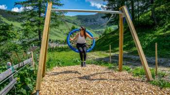 Une femme se balance dans les montagnes du Liechtenstein et profite de la vue