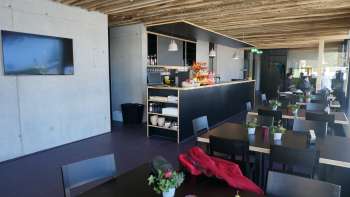 Salle de restaurant moderne avec des tables sombres, des compositions florales fraîches et un toit en bois rustique