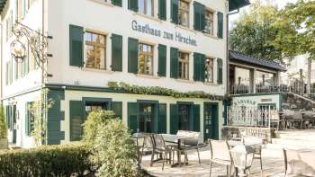Terrasse accueillante avec tables et chaises en bois devant l'Gasthaus zum Hirschen