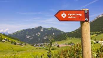 Panneau indicateur parcours du cœur alpin avec le village de montagne de Malbun en arrière-plan