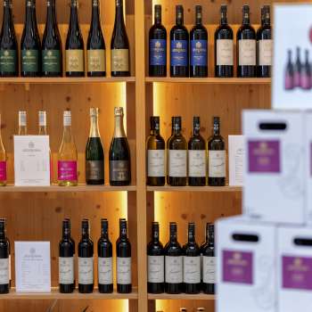Intérieur de la cave avec des étagères en bois élégamment éclairées remplies de bouteilles et de cartons de vin.