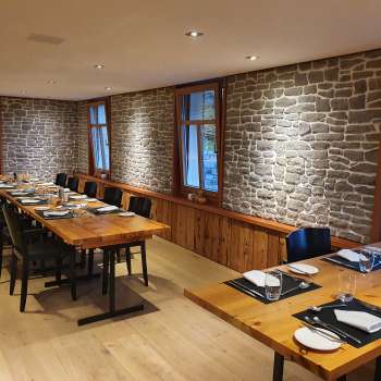 Salle de restaurant élégante avec de longues tables en bois, des murs en pierre et une décoration moderne