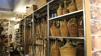 Étagères avec des outils traditionnels, des bouteilles en osier et des objets du quotidien Étagères avec des outils traditionnels, des bouteilles en osier et des objets du quotidien