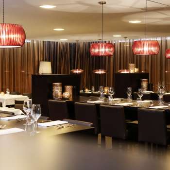 Salle de restaurant élégante avec des meubles sombres, des lampes design rouges et une ambiance raffinée