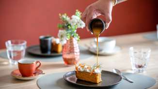 Une main verse de la sauce caramel sur une pièce de dessert dans le restaurant stylé RUUF du b_smart Hotel Kloster Schaan au Liechtenstein